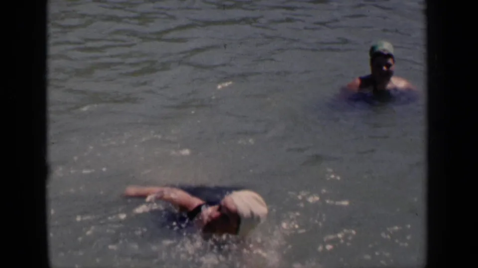 1951 New York 8mm frame with a woman swimming near the lower edge and a second capped swimmer upright in the water behind her.