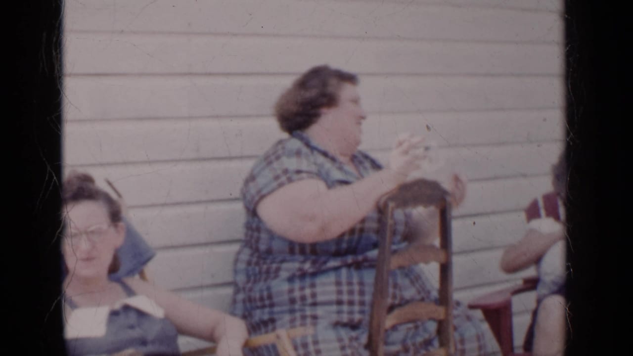 Three adult women sit outside, with one woman in plaid turned to the side.