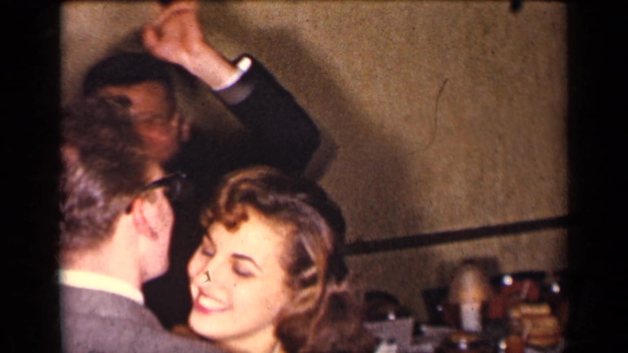 Smiling woman at a crowded formal dance with men and party guests around her.