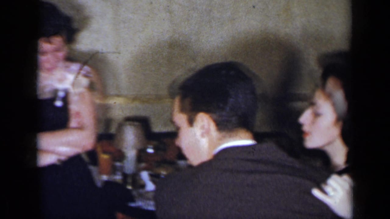 Couple seated or standing close together beside tables in a formal room.