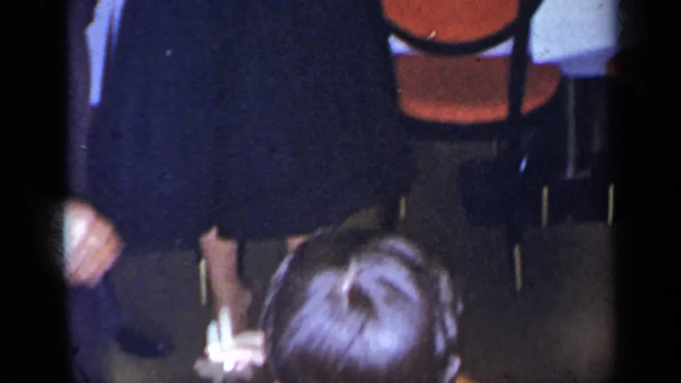 1954 New York 8mm frame of guests dancing closely in a dim private interior with chairs and tables in view.