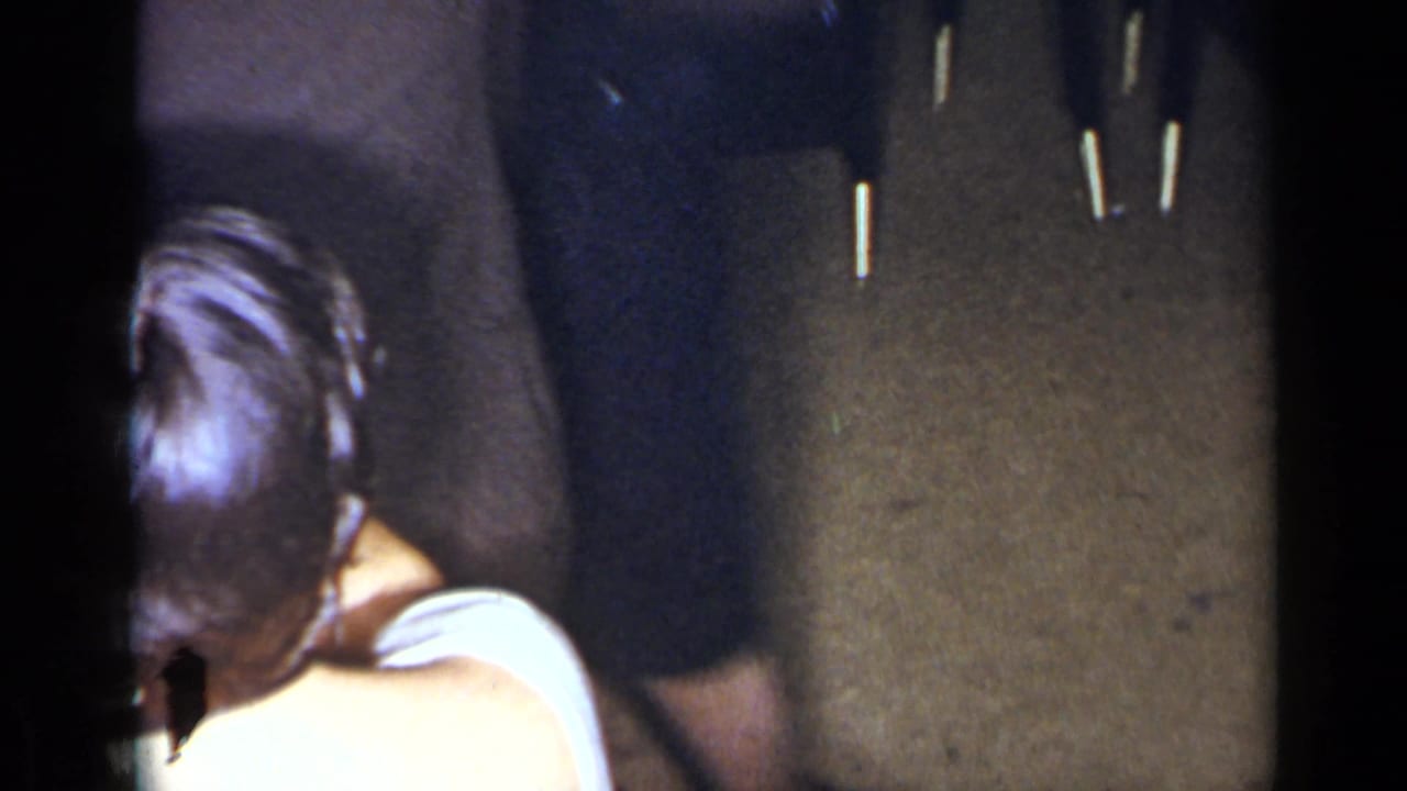 Guests in dark clothing stand near a person in a light top, seen from a close handheld angle.