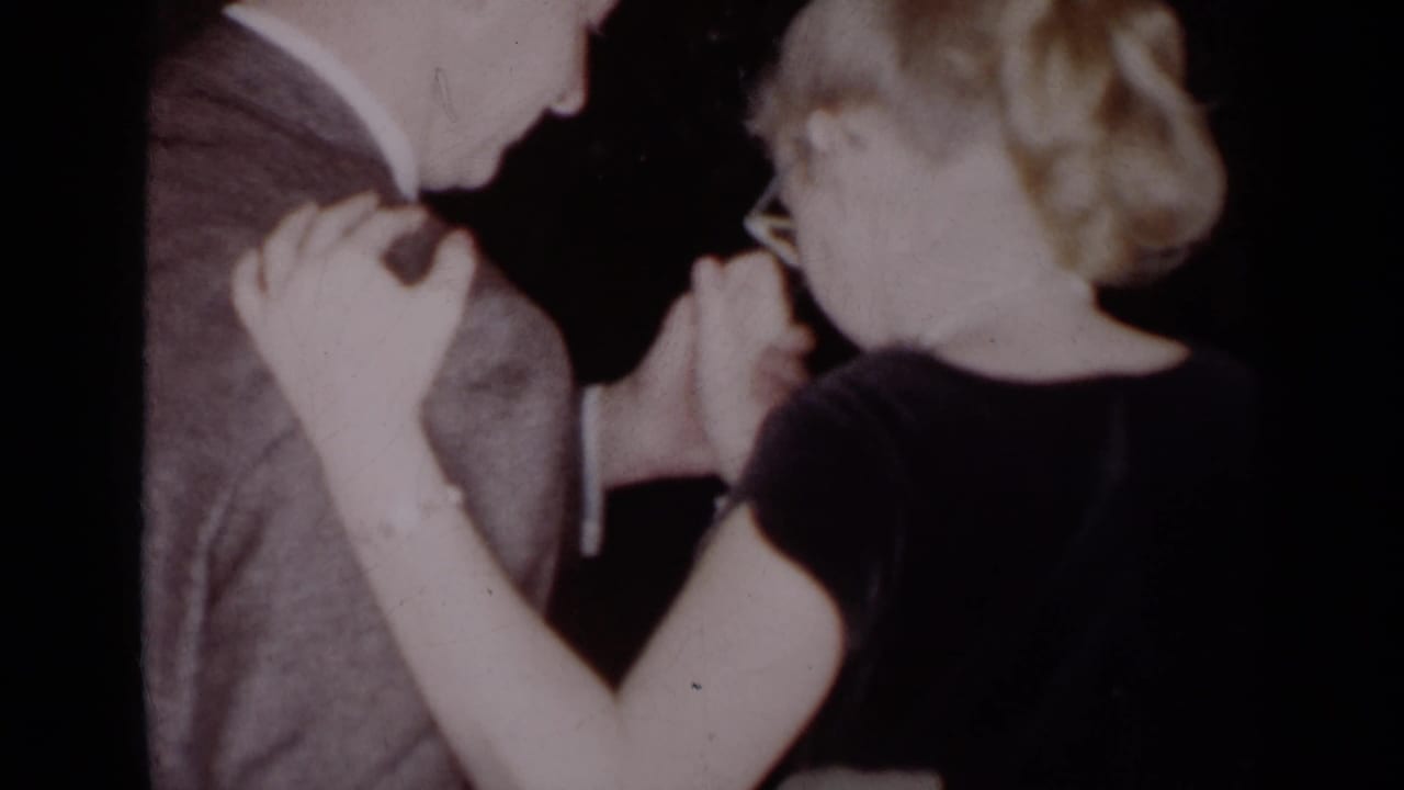 Close view of a couple dancing with clasped hands, the man in a gray suit and the woman in a dark top.