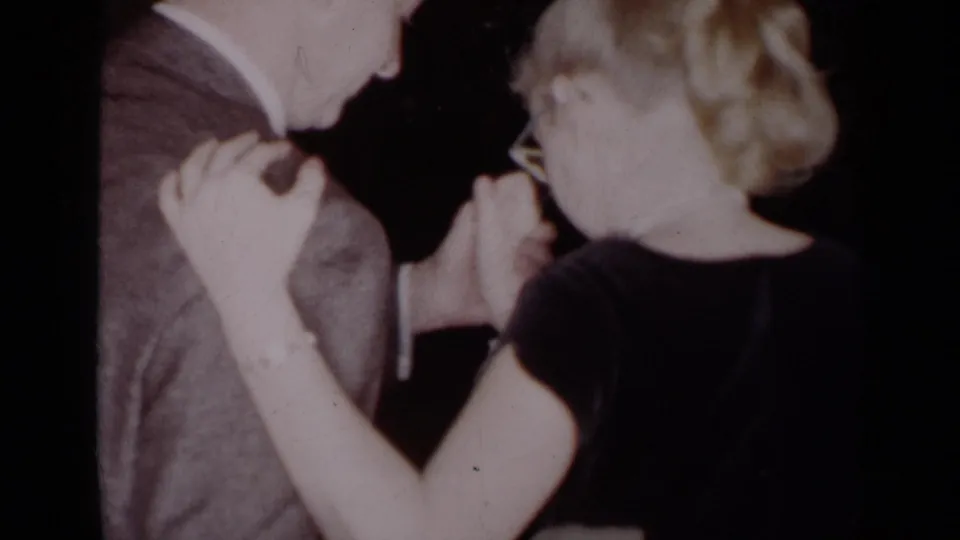 1954 New York home-movie frame showing a couple dancing close together, with clasped hands and soft 8mm exposure.