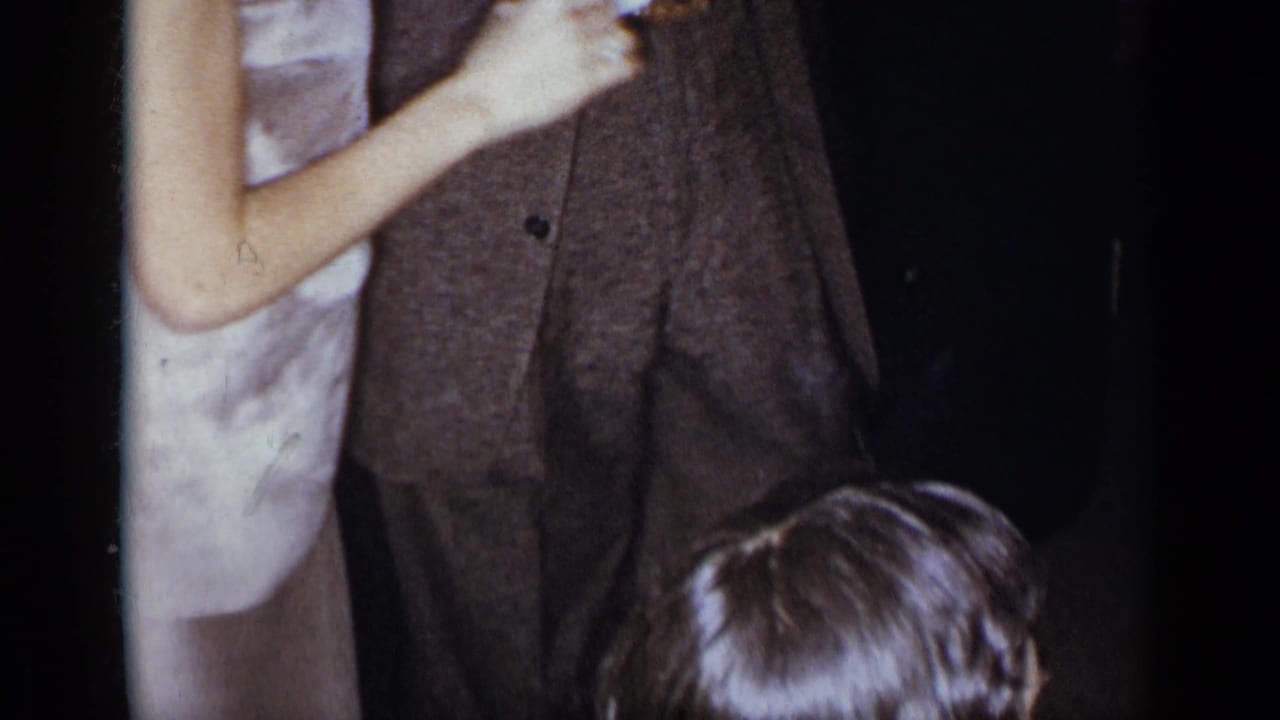Cropped dancers in formal clothing with a child's head low in the frame.