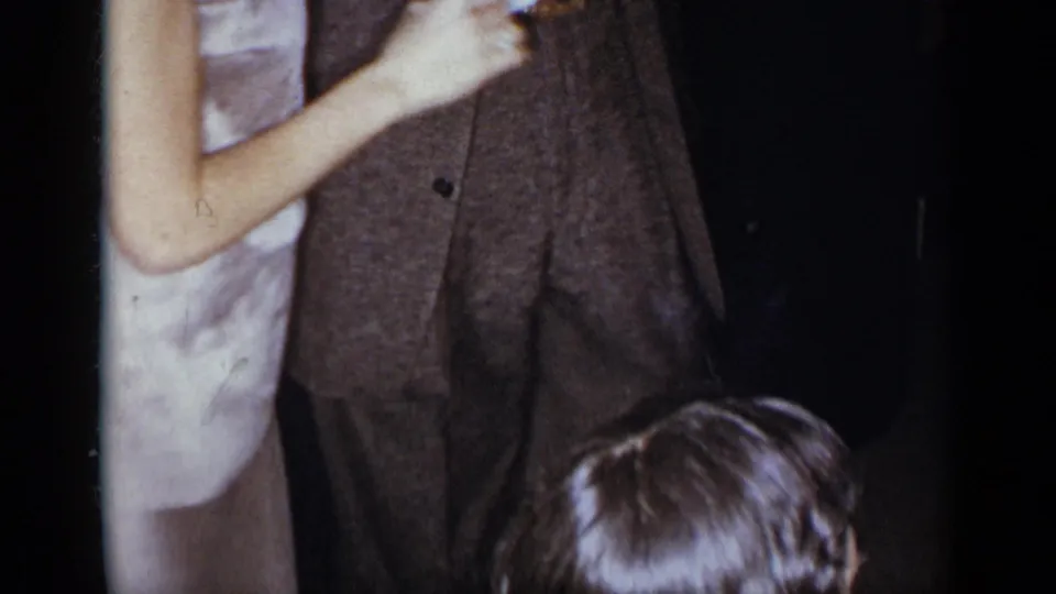 1954 New York home-movie frame showing cropped adults dancing in formal clothing, with a child's head partly visible at the bottom.