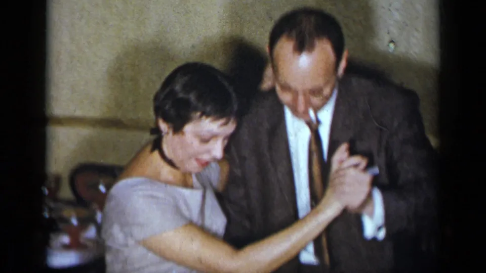 The dancing couple is framed from slightly above, with the suited man smoking and the woman in a light dress looking downward.