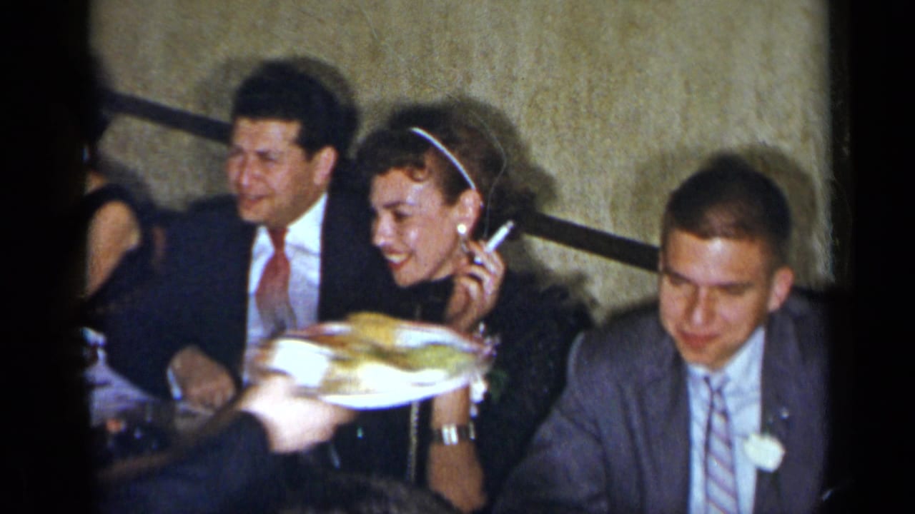 1954 New York party scene with seated guests, a woman holding a cigarette, and a serving tray passing in front.