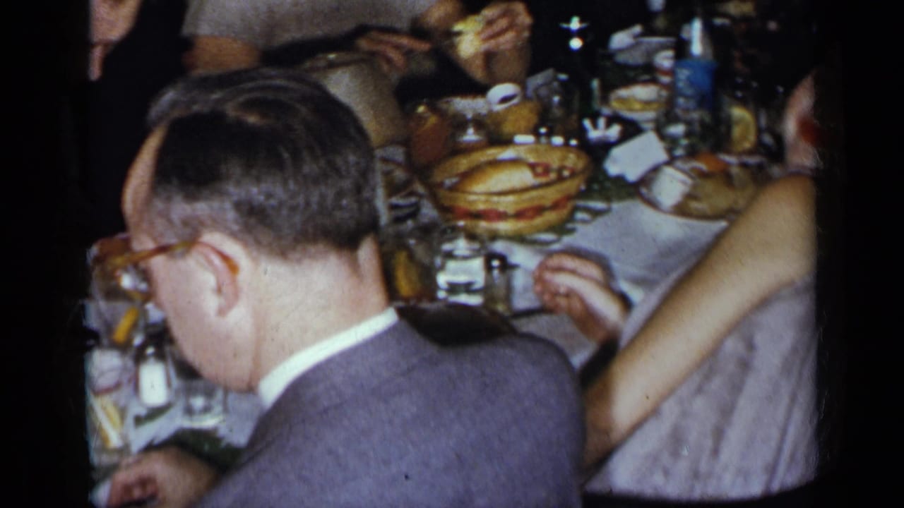 Man in glasses seated at a crowded dinner table with plates and serving dishes.