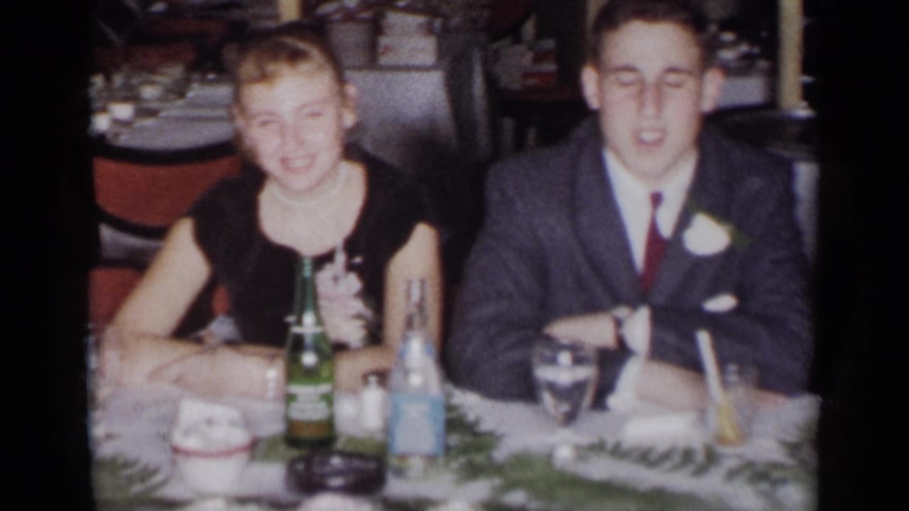Woman and young man seated at a table with bottles and glassware.