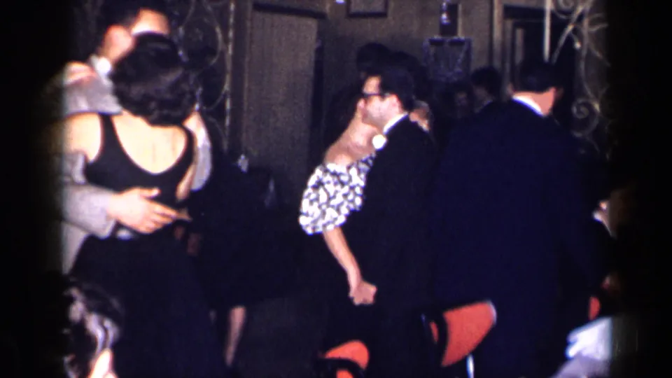 1954 New York party footage shows couples embracing while dancing, with suited guests and formal dresses visible in low light.