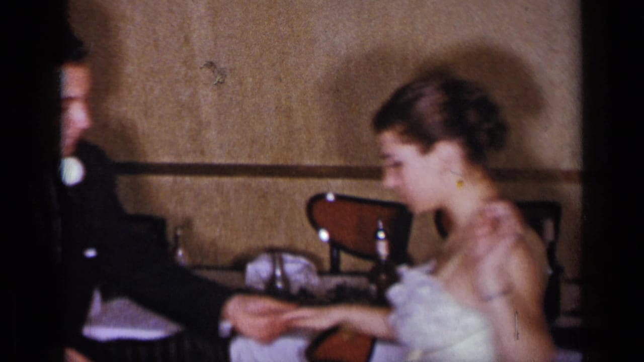 Man and woman in formal wear sit at a table, with the woman turned toward the man.