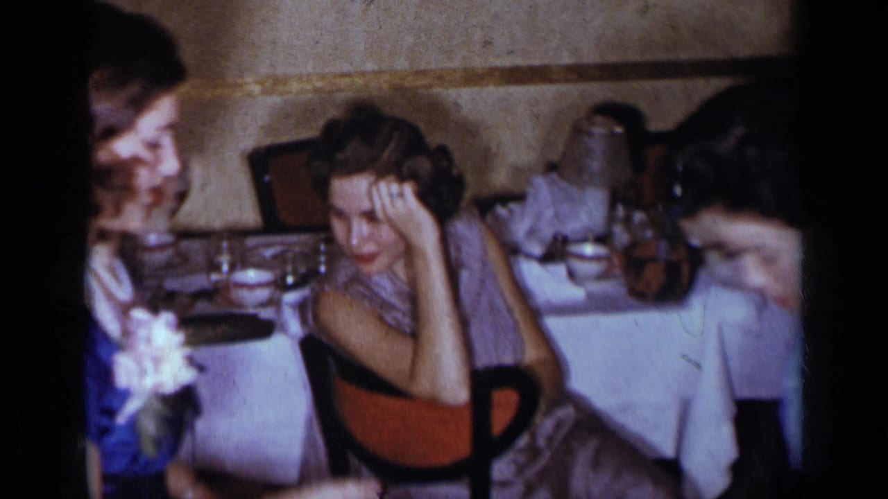 Two young women seated at a formal dinner table with glassware and white linens.