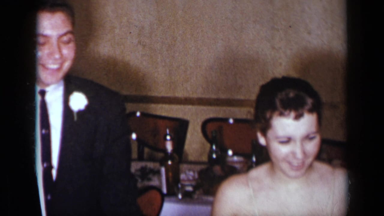 Bride seated near a smiling man in a dark suit at a banquet table.
