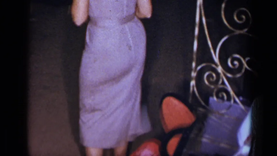 Near a wrought-iron screen and red chairs, the woman in a pale purple dress remains in view at the New York formal reception.