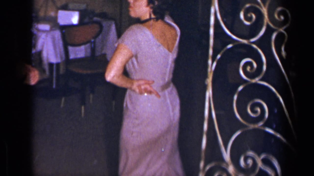 Woman seen from behind in a sparkly purple dress near chairs and decorative metalwork.