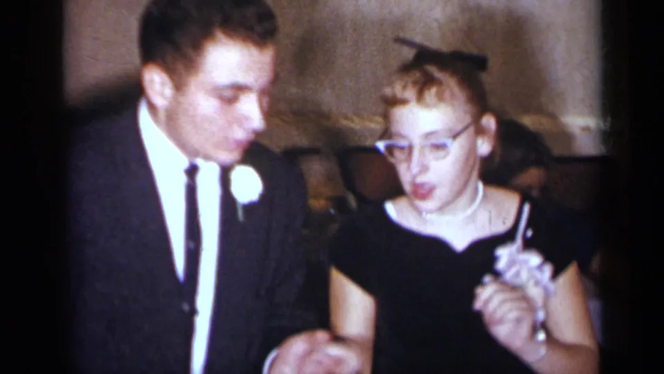In the final frame, the young couple faces the camera while dancing, the woman wearing glasses and holding a corsage.