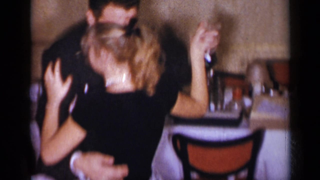 Woman raises one arm while dancing with a man in a dark suit.