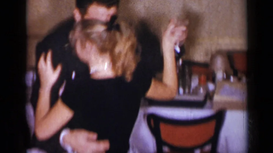 Adult couple dancing in a dim New York restaurant setting, with the woman turning and raising her arm.
