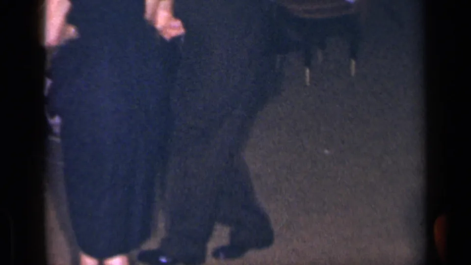 1954 New York frame with cropped adults in dark formal clothing, shoes and movement across a dimly lit event floor.