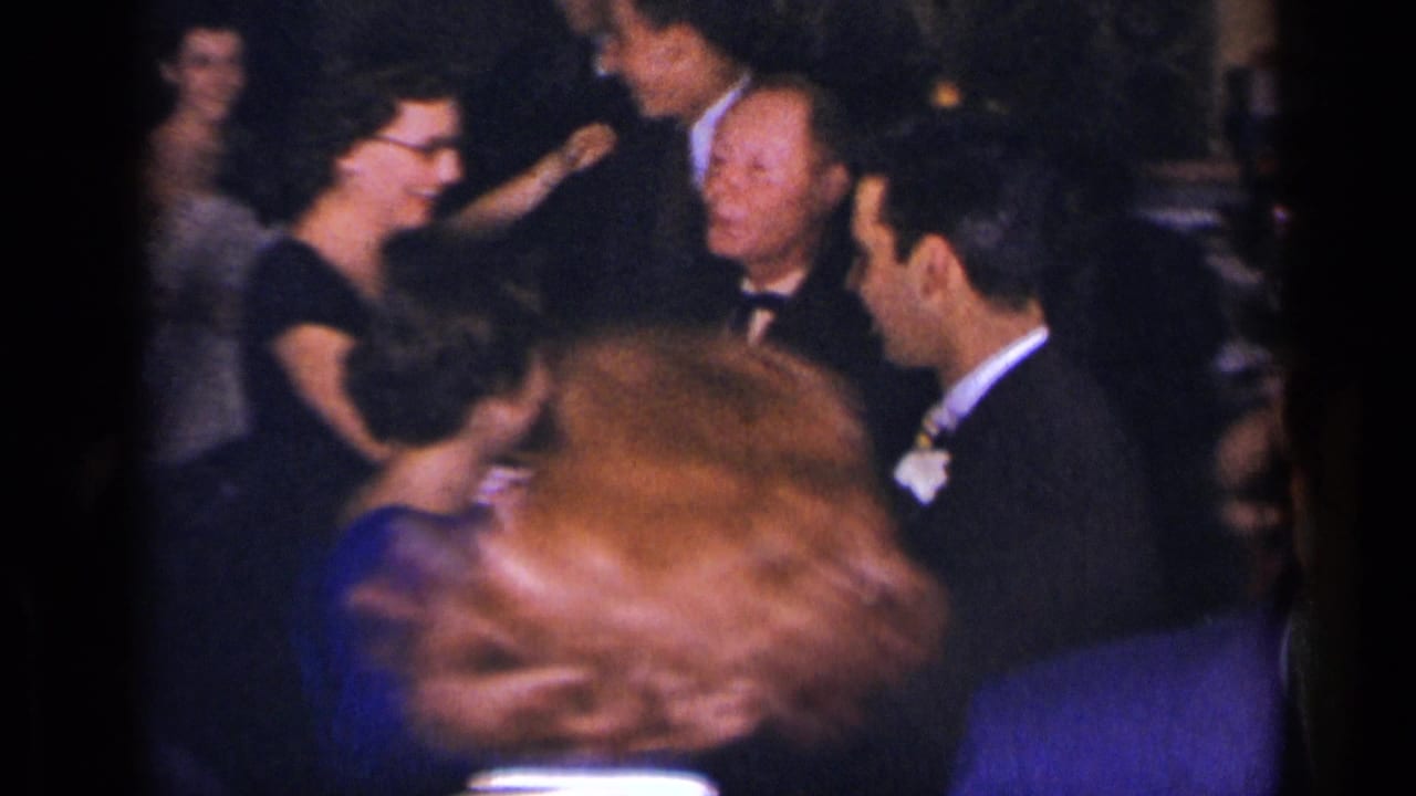 1954 New York party scene with suited men and women in dresses gathered and dancing in low light.