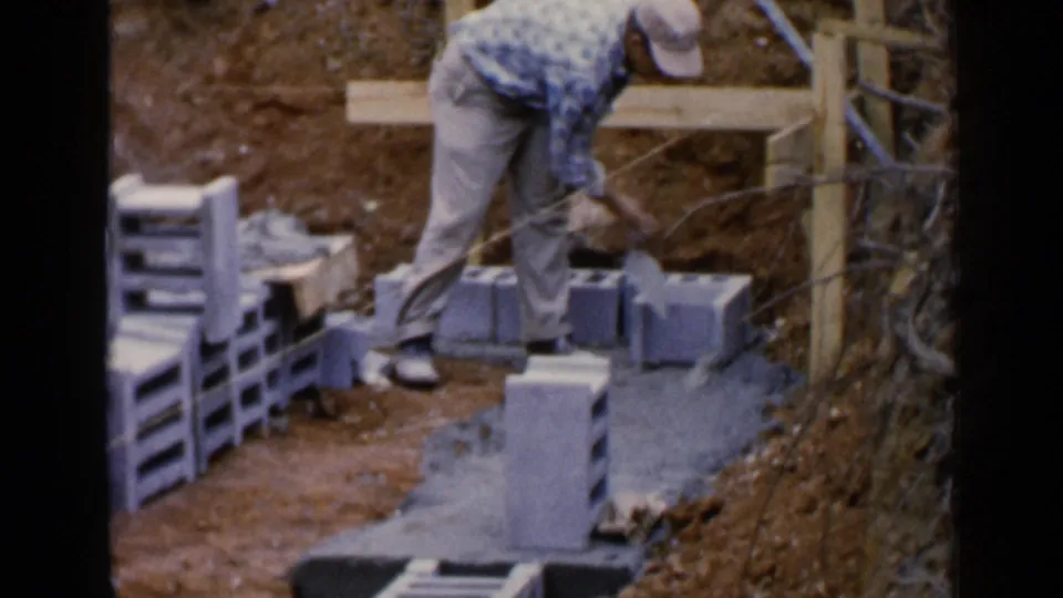 A man applies or adjusts mortar on cinder blocks at an outdoor Birmingham construction site in 1957.
