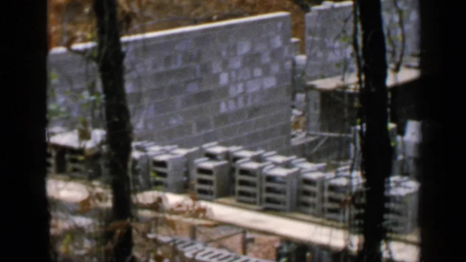 Partially built cinder block wall in Birmingham with stacked concrete units, timber planks, and trees in the foreground.