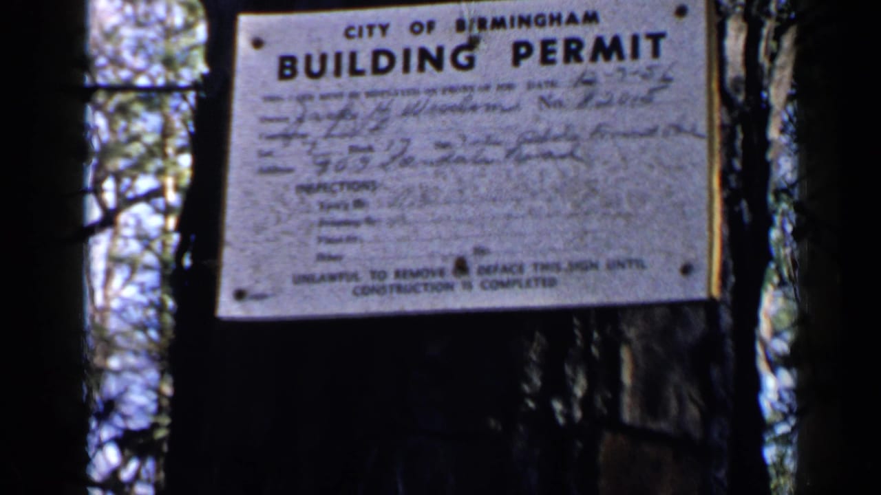 City of Birmingham building permit sign posted on a tree in a wooded area.