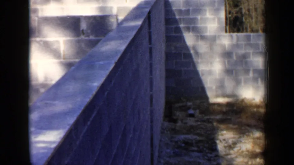 Low-angle view of a concrete foundation edge and cinder block wall at the Birmingham construction site shown in the clip.