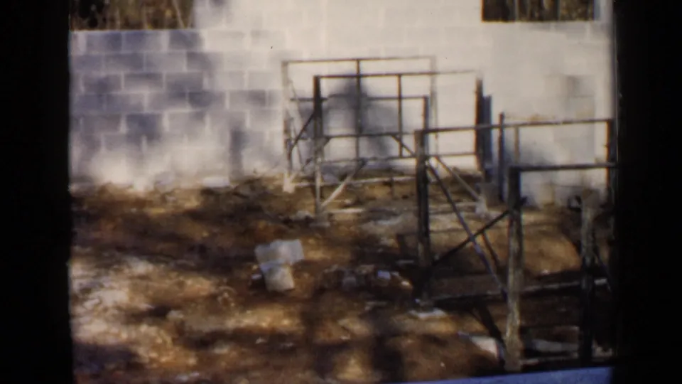 1957 Birmingham frame showing scaffolding, cinder block masonry, and construction debris across a bare work area.