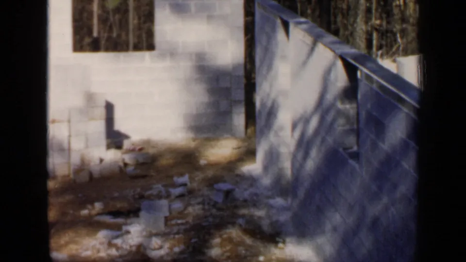 1957 Birmingham home-movie view of a cinder block corner, open wall sections, and loose materials on the ground.