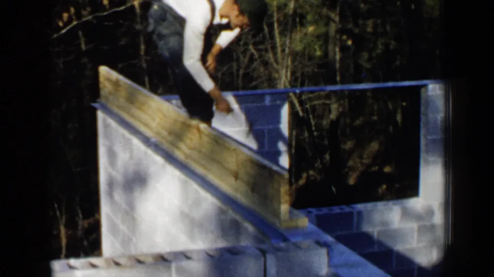 Close 8mm frame of a worker on an unfinished cinder block wall with a long beam set at an angle.