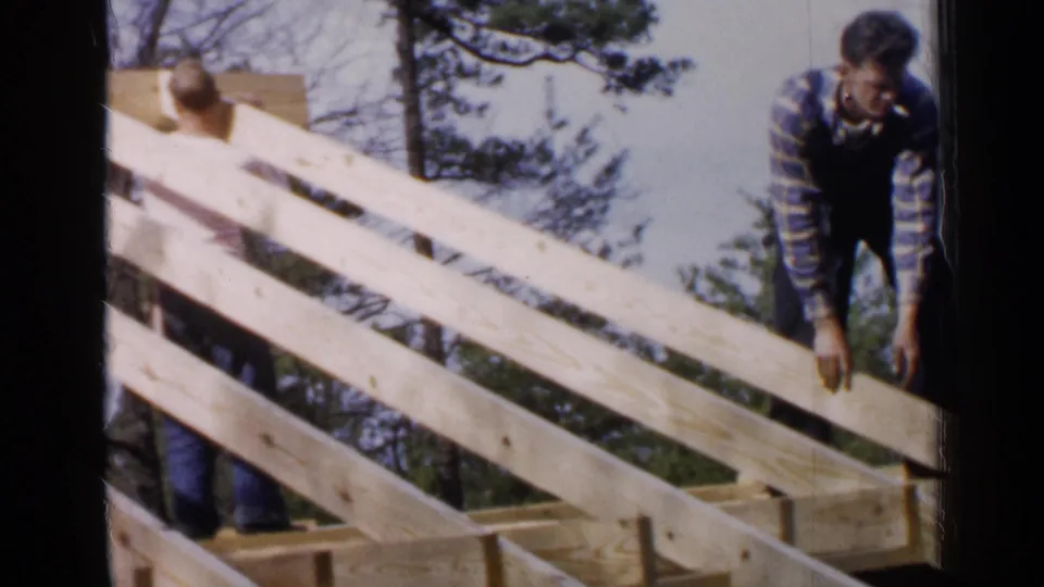 The final frame shows two adult men behind angled rafters, with one bending near the edge of the structure.
