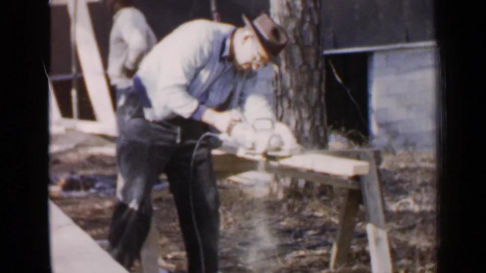 The final frame shows the man still focused on cutting the plank, with the tree, yard, and building exterior behind him in Birmingham, 1957.