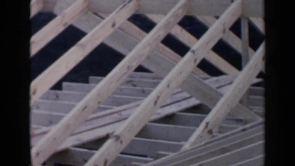 Close 1957 Birmingham construction frame showing crossed wooden supports and roof boards in an unfinished house structure.