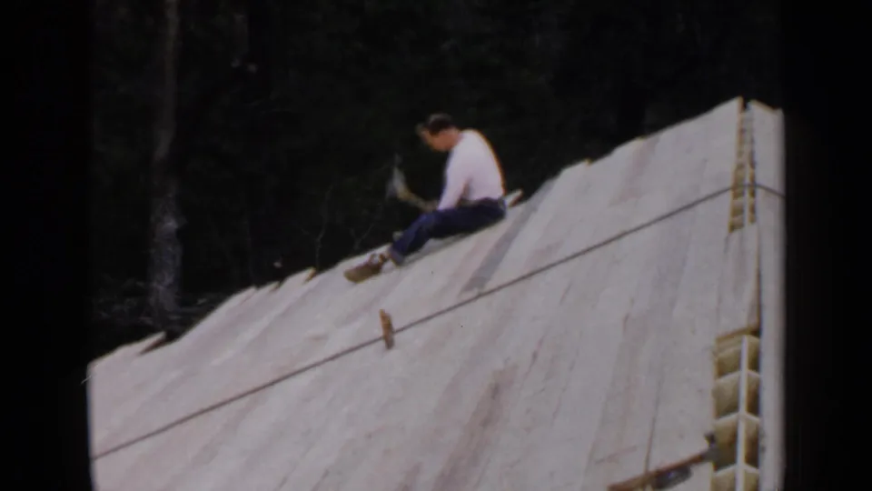 In the final frame, the man holds a hammer while seated on the sloped white-covered wooden structure, with a rope line crossing the surface.