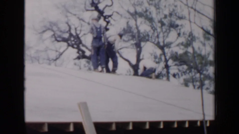 The closing frame shows men grouped on a sloped roof, with roof framing and bare trees visible in the 1957 Birmingham scene.
