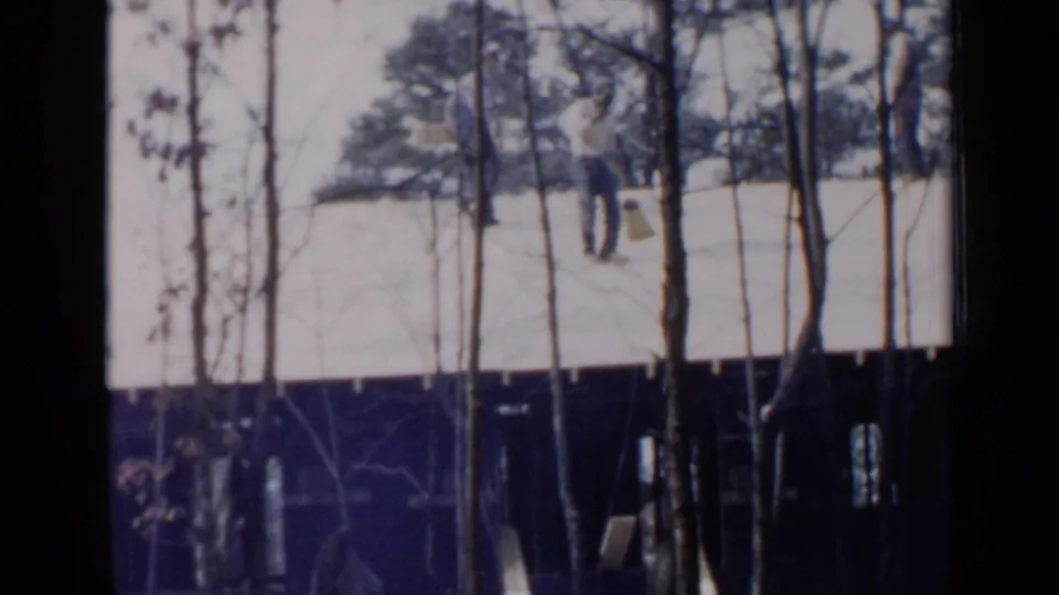 The final frame shows two distant people on a snow-covered roof, partly obscured by trees and soft 8mm blur.
