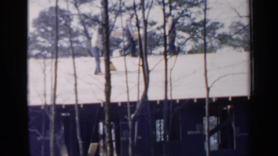 A distant worker moves across the roof of a house under construction in Birmingham, Alabama, in 1957 archival 8mm footage.