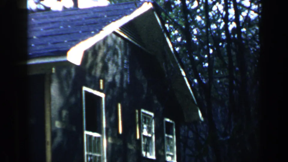 1957 Birmingham frame of a wooded residential exterior, showing roof shingles, dark siding, windows, and tree shadows.