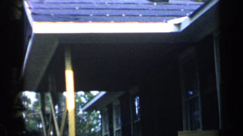 The home-movie view tilts along the roof and eaves of a Birmingham residence, with a partial person at the left edge.