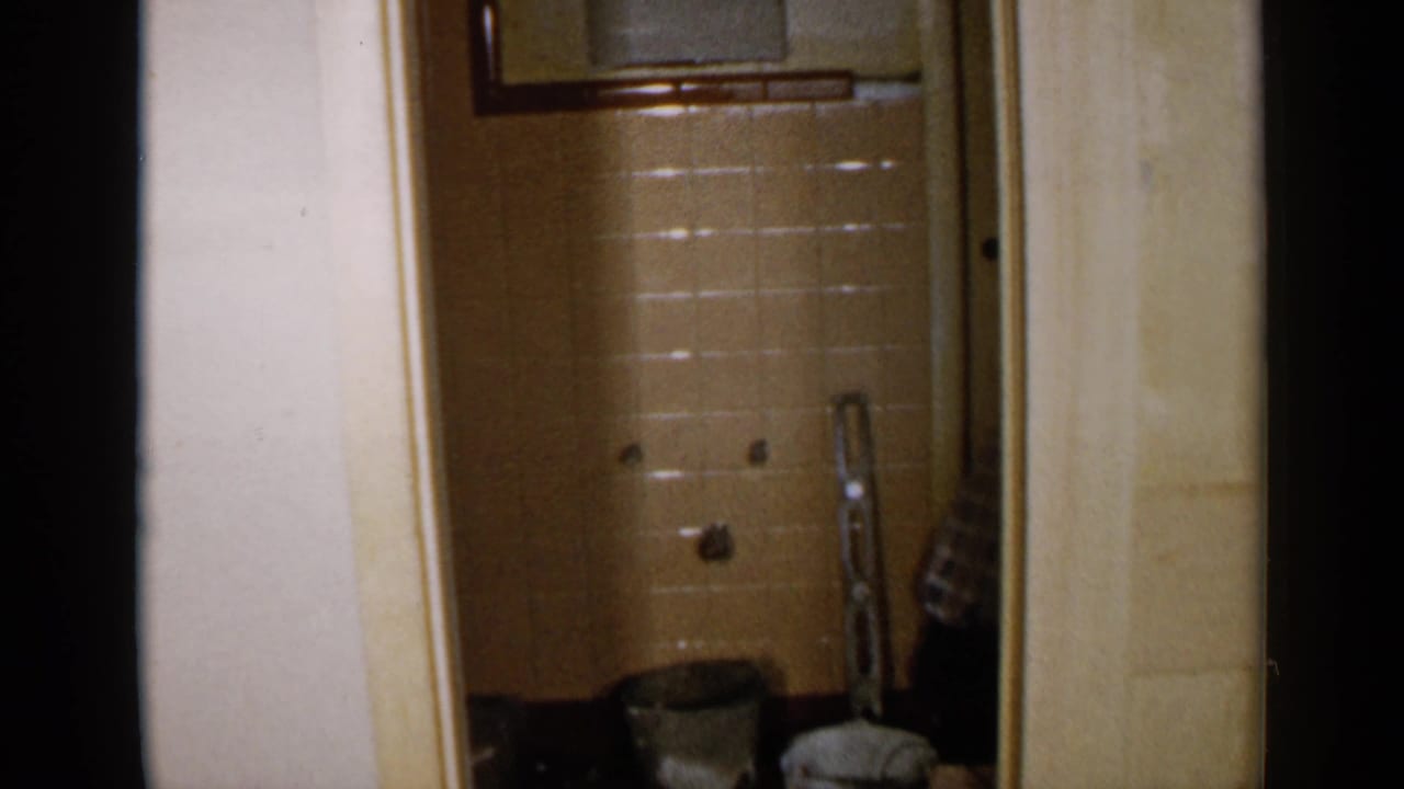 1957 Birmingham home-movie frame showing an interior doorway toward a tiled bathroom or shower area during renovation.