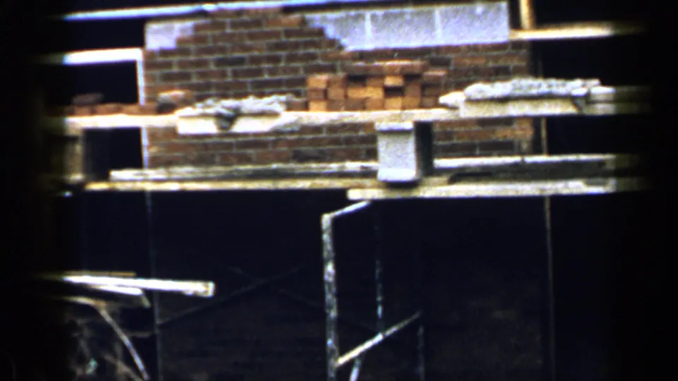 1957 Birmingham construction scene showing stacked red bricks, concrete blocks, planks, and a dark interior partition.