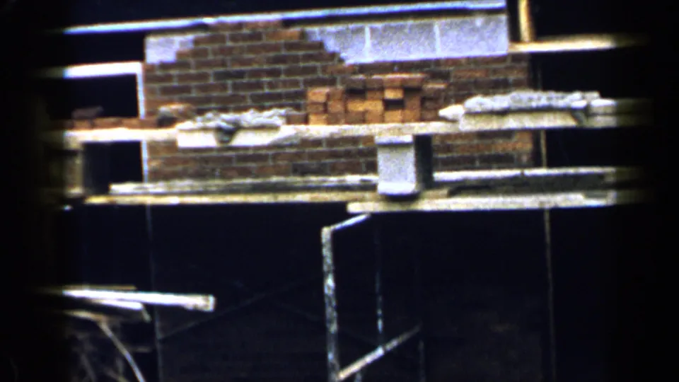 Stacks of red bricks, concrete blocks, and scaffold boards appear inside a Birmingham construction area in 1957 footage.