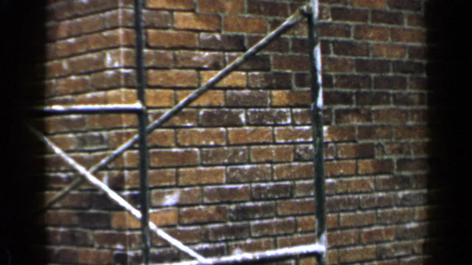 Close 8mm view of a Birmingham brick exterior with metal scaffolding crossing the frame.