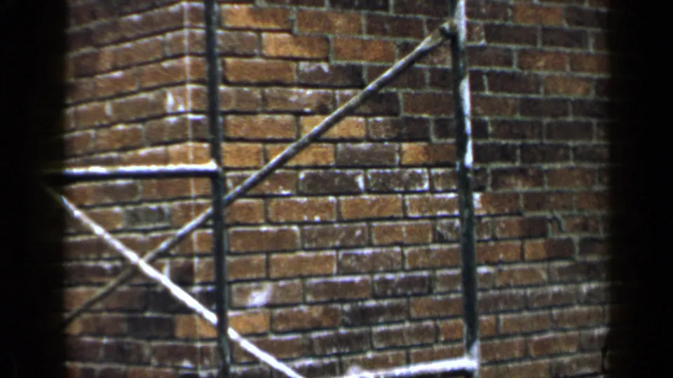 Steady 8mm frame of a Birmingham brick wall corner with scaffolding against the exterior surface.