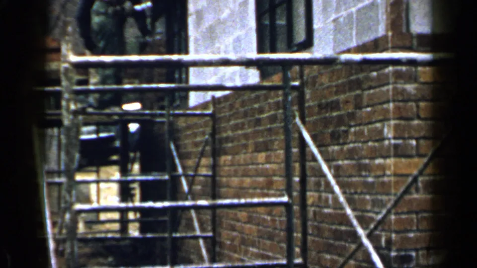 Scaffolding crosses a brick corner and concrete wall during construction in Birmingham, Alabama, in the 1957 clip.