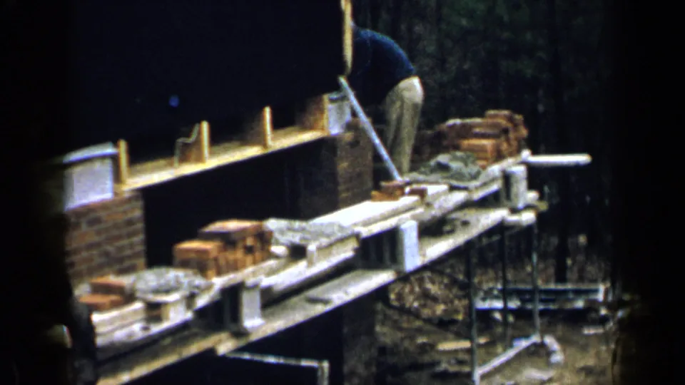 1957 Birmingham 8mm frame with the worker partly off to one side while the brick wall and scaffold remain visible.