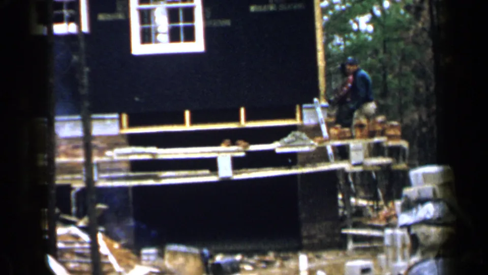 A worker in a cap stands on the scaffold near stacked bricks outside the Birmingham house under construction.