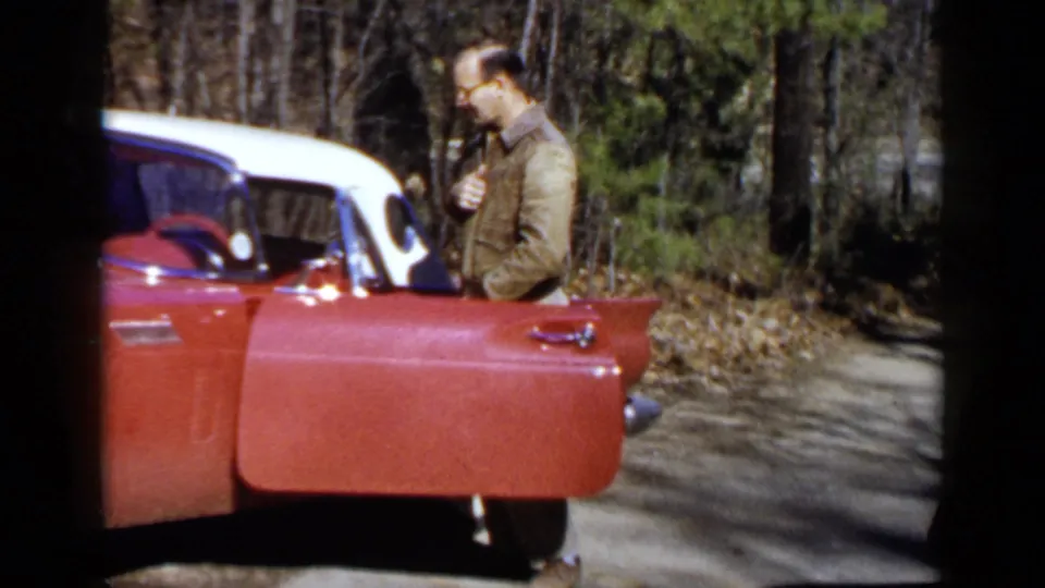 In the Birmingham 1957 footage, a man in glasses stands beside the open driver's door of the red and white Thunderbird.